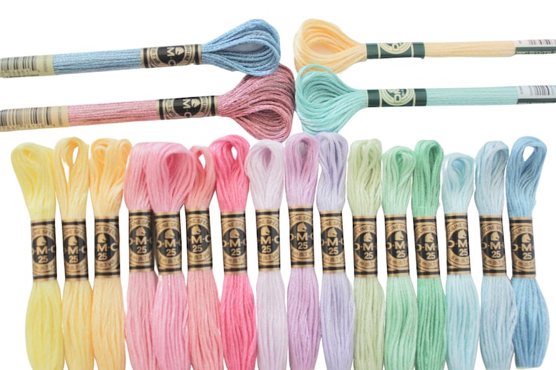 May include: A collection of colorful embroidery floss skeins in various pastel shades, including yellow, pink, blue, and green. Each skein is labeled with "DMC 25". The floss is neatly arranged, showcasing a range of soft, vibrant hues.