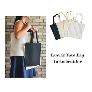 Könnte beinhalten: Fünf Canvas-Tragetaschen, zwei schwarze und drei naturweiße, mit Henkeln. Der Text "Canvas Tote Bag to Embroider" befindet sich unter den Taschen.