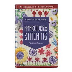 Op de afbeelding: Een boek getiteld "Embroidery Stitching" van Christen Brown. De omslag toont kleurrijke geborduurde bloemmotieven, waaronder zonnebloemen, rode bloemen en paarse knoopaccenten. Tekst op de omslag luidt "30+ Stitches | All the Basics & Beyond" en "Handy Pocket Guide".
