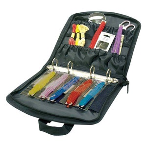 May include: Black zippered carrying case with a clear plastic insert for storing embroidery floss. The case has multiple pockets and a ring binder for organising floss. It also includes a magnifying glass, scissors, and needles.