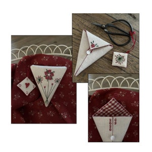 May include: Three white fabric needlepoint pouches with red accents. One pouch features a red flower design, another has a red and white gingham pattern, and the third has the text "2020" embroidered on it.
