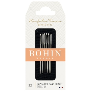 以下が含まれることがあります： Bohin Franceのタペストリー針のパッケージ。パッケージは、"Manufacture Fran&ccedil;aise Depuis 1833"と"BOHIN FRANCE"のテキストが入った白とピーチ色の背景です。6本の銀色の針が黒い背景に表示されています。"TAPISSERIE SANS POINTE TAPESTRY"のテキストも表示されています。