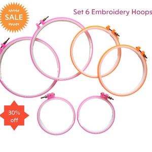 May include: Set of six embroidery hoops in pink and orange. The hoops are made of plastic and have a white inner ring. The hoops are arranged in a circle with the largest hoop at the top and the smallest hoop at the bottom. The text "Set 6 Embroidery Hoops" is written above the hoops. The text "SALE" is written on a starburst in the top left corner. The text "30% off" is written on a starburst in the bottom left corner.