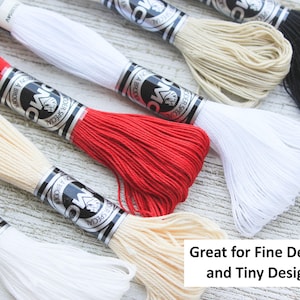 May include: Assortment of DMC embroidery floss spools in various colors, including red, white, and beige. The spools are labeled with the DMC logo and the text "Der Special" in black lettering.