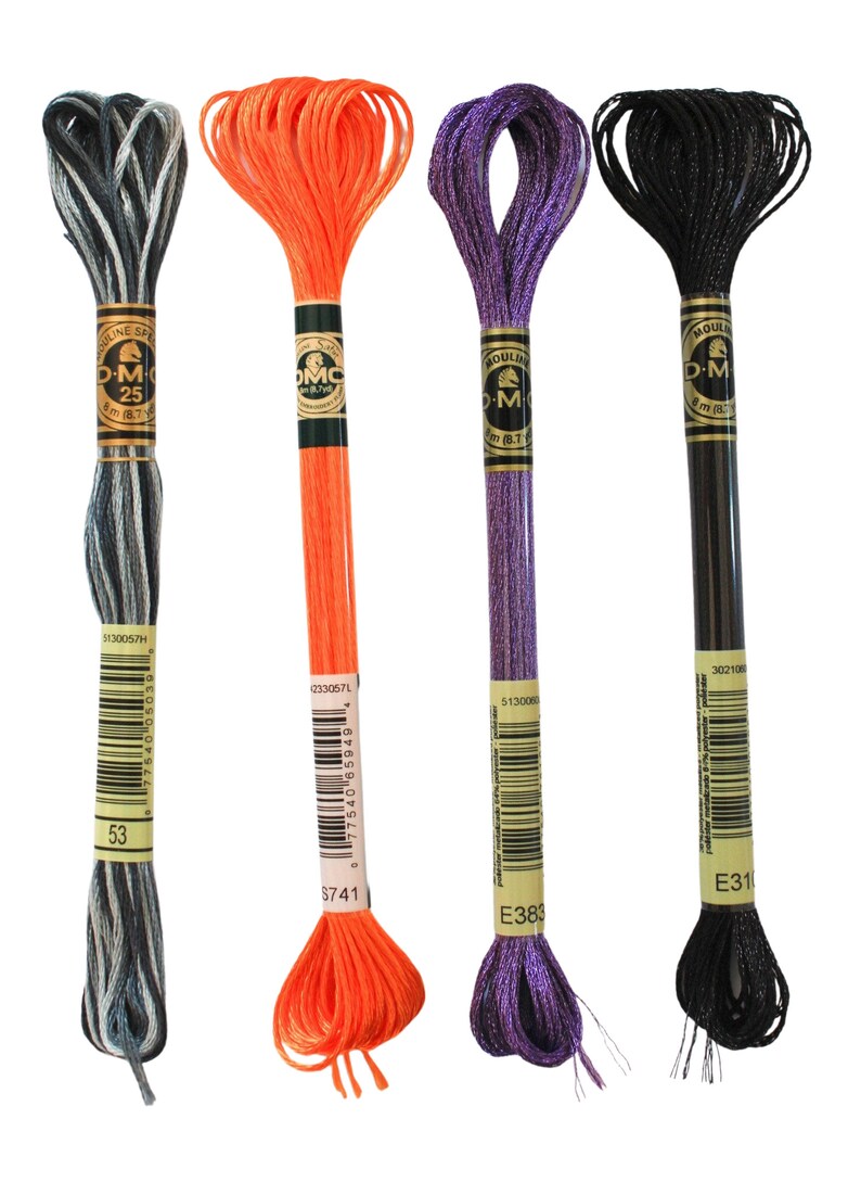 May include: Four spools of DMC embroidery floss in black, orange, purple, and a silver and black variegated color. The spools are labeled with the DMC color numbers and names: 302106 E31, 233057L S741, 513000 E383, and 5130057H 53.