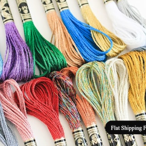 Puede incluir: Una variedad de carretes de hilo de bordar de colores brillantes con hilos metálicos. Los carretes están etiquetados con "DMC" y "Mouline". Gastos de envío fijos.