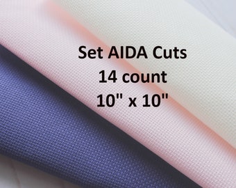 May include: Set of three 10 inch by 10 inch Aida fabric squares in white, pink, and blue. The fabric is 14 count.