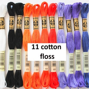 May include: Eleven spools of DMC embroidery floss in white, black, orange, and purple. The spools are labeled with DMC numbers: B5200, 310, 970, 721, 608, 155, 3746, 333, and 158.