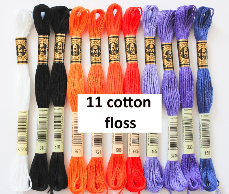 May include: Eleven spools of DMC embroidery floss in white, black, orange, and purple. The spools are labeled with DMC numbers: B5200, 310, 970, 721, 608, 155, 3746, 333, and 158.