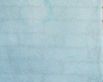 May include: A light blue fabric with a textured appearance. The fabric has a subtle, horizontal striped pattern and a slightly wrinkled texture. The color is a soft, muted shade of blue, with some areas appearing lighter than others.