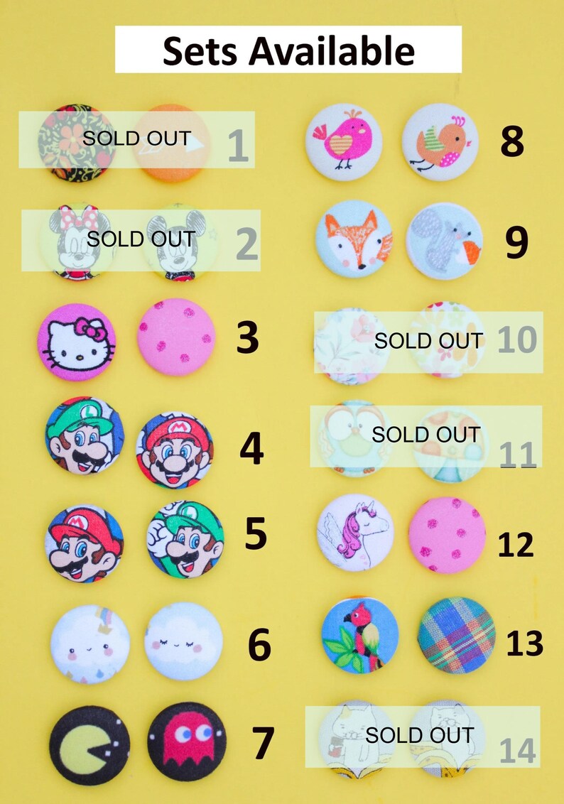 a collection of 14 colorful buttons, each with a unique design, arranged in two rows against a yellow background. The buttons are labeled with numbers 1 through 14, indicating that they are available for purchase.