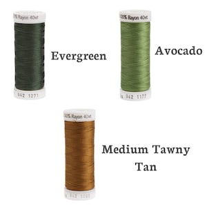Puede incluir: Tres carretes de hilo de ray&oacute;n 100% en los colores verde esmeralda, aguacate y marr&oacute;n tostado medio. Los carretes est&aacute;n etiquetados con el peso del hilo y el nombre del color.