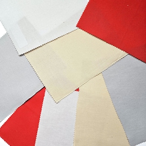 May include: A collection of fabric swatches in various colors, including red, gray, cream, and white. The swatches are arranged in a scattered pattern, showcasing the different textures and hues of the materials. The edges of the swatches have a decorative, scalloped trim.