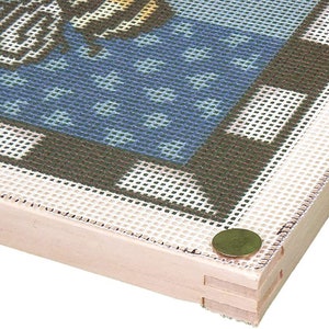Op de afbeelding: Een houten frame met een wit gaasdoek erover gespannen. Het doek is met messing spijkers aan de randen van het frame bevestigd.