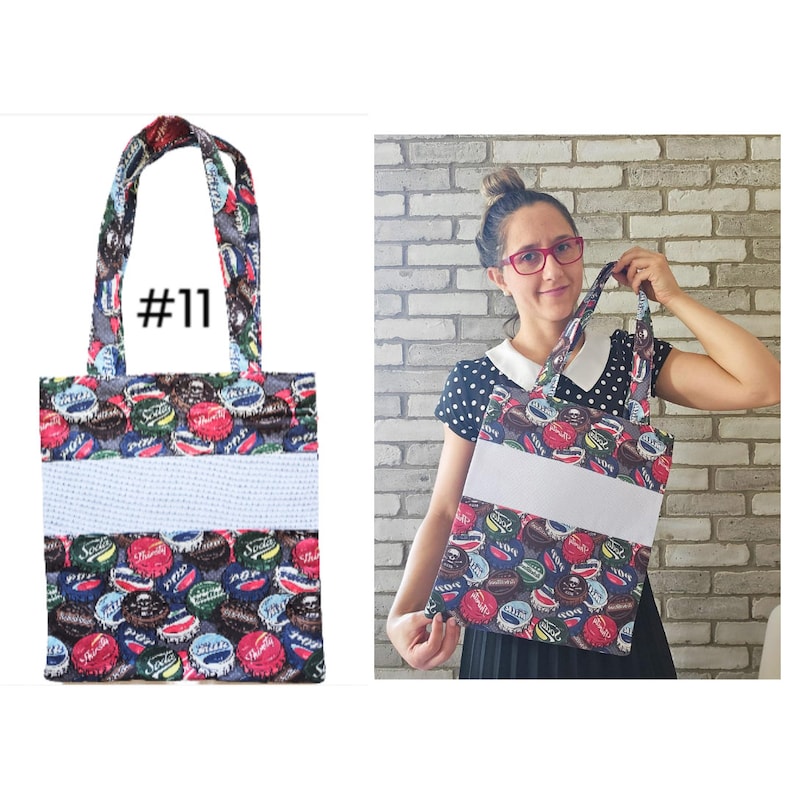 May include: A tote bag with a white and blue striped fabric panel and a colorful bottle cap print. The bag has a #11 tag on the front.