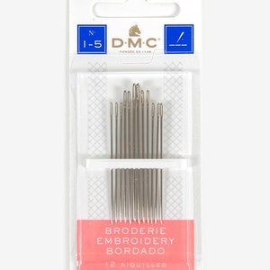 Puede incluir: Un paquete de 12 agujas de bordar en un contenedor de pl&aacute;stico transparente con una etiqueta rosa y blanca. La etiqueta dice "Broderie Embroidery Bordado" y "12 Aiguilles Needles Agujas". El paquete est&aacute; etiquetado con el logotipo de DMC y el n&uacute;mero "1-5".