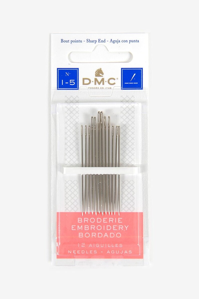 Puede incluir: Un paquete de 12 agujas de bordar en un contenedor de pl&aacute;stico transparente con una etiqueta rosa y blanca. La etiqueta dice "Broderie Embroidery Bordado" y "12 Aiguilles Needles Agujas". El paquete est&aacute; etiquetado con el logotipo de DMC y el n&uacute;mero "1-5".