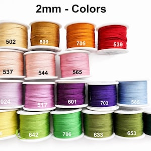 May include: A collection of 2mm ribbon spools in various colors, each labeled with a specific number. The colors include shades of yellow, orange, red, pink, purple, blue, and green. The text 2mm - Colors is displayed at the top of the image.