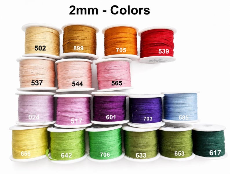 May include: A collection of 2mm ribbon spools in various colors, each labeled with a specific number. The colors include shades of yellow, orange, red, pink, purple, blue, and green. The text 2mm - Colors is displayed at the top of the image.