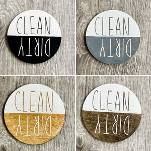 May include: Four round wooden signs with a black, gray, brown, and white background. Each sign is divided in half with the top half saying "CLEAN" and the bottom half saying "DIRTY".