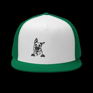 May include: A white and green trucker hat with a black and white illustration of a German Shepherd dog peeking out from behind the brim.