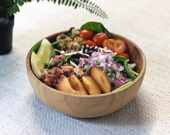 May include: A wooden bowl filled with a colourful salad. The salad includes spinach, red onion, cherry tomatoes, dried cranberries,  sliced plums, and a meat mixture.