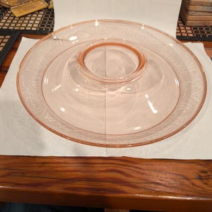 May include: A vintage pink glass serving dish with a raised center bowl. The dish has a delicate etched design around the rim.