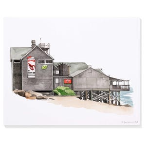 May include: Watercolor painting of a weathered, gray wooden building on pilings, with a sign that says "Ocean Mkt" and a lobster graphic. A smaller sign reads "O's". The building is on a sandy beach with a view of the ocean.