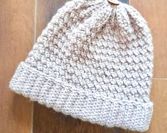 May include: A beige crocheted beanie hat with a textured stitch pattern.