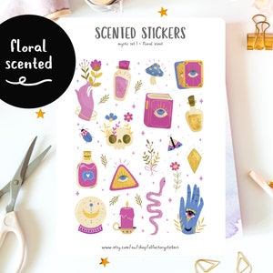May include: A sheet of floral scented stickers with a mystical theme. The stickers feature a variety of designs, including a skull, an eye, a hand, a snake, a candle, a crystal, a book, a bottle, a mushroom, a butterfly, and a ladybug. The stickers are printed on white paper and have a floral scent.