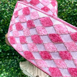 May include: Pink and white checked ribbon with a fuzzy texture. The ribbon is rolled up on a spool.