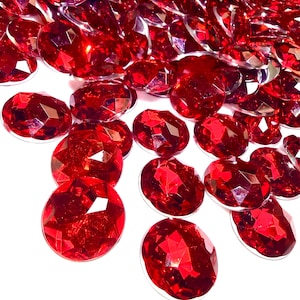 May include: A collection of numerous oval-shaped, faceted red acrylic gems. Each individual piece features a polished, reflective surface with multiple geometric cuts that catch the light, creating a vibrant, deep crimson appearance throughout.