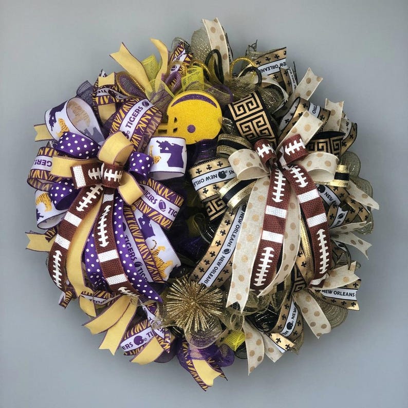 May include: A decorative wreath featuring football-themed ribbons in purple, gold, and brown. The wreath includes a small yellow football helmet and ribbons with the text "Tigers" and "New Orleans".
