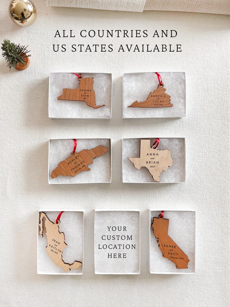 May include: Wooden ornaments in the shape of US states and countries, each with names and dates, presented in individual boxes. The text "ALL COUNTRIES AND US STATES AVAILABLE" is at the top. One box is blank, with the text "YOUR CUSTOM LOCATION HERE".