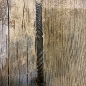 May include: A black twisted metal door handle with a rounded end.