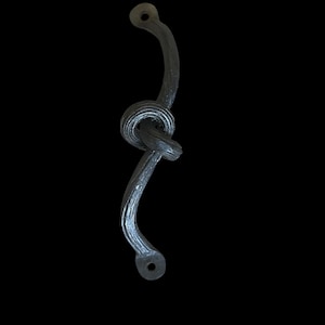 Może przedstawiać: Czarny metalowy klamka do drzwi z wzorem węzła. Klamka ma dwa okrągłe otwory u góry i na dole.