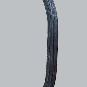 May include: Black metal door handle with a textured, ridged design. The handle is curved and has a rounded top.