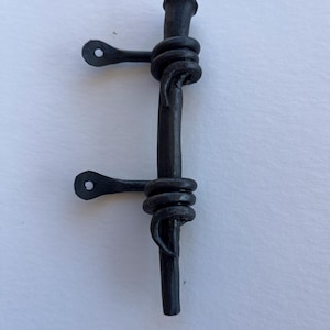 May include: Black metal door hinge with two loops and a decorative twist. The hinge is designed to be mounted on a door or gate.