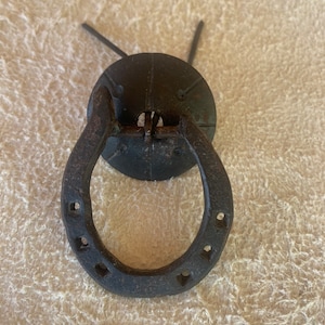 May include: Black metal horseshoe door handle with a round plate and two small holes.
