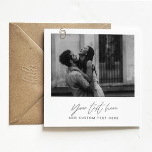 Puede incluir: Impresi&oacute;n estilo polaroid en blanco y negro con una pareja riendo y abraz&aacute;ndose. La impresi&oacute;n incluye el texto "Your text here" y "Add custom text here". Tambi&eacute;n se ve un sobre marr&oacute;n y un clip en forma de coraz&oacute;n.