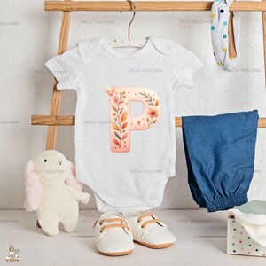 May include: A white baby bodysuit featuring a floral "P" design, alongside blue trousers, white shoes, and a soft toy bunny. The letter "P" is adorned with flowers, leaves, and hearts. The image includes the text "Hello happiness".
