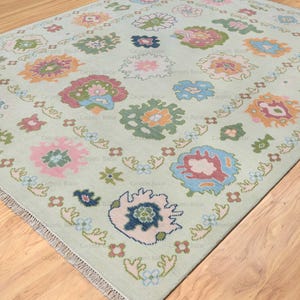 light green oushak rug by carpet bazaar with baby pink, coral, blue, green and orange abstract floral pattern.