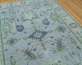 Könnte beinhalten: Ein hellblauer Teppich mit traditionellem persischem Design. Der Teppich zeigt komplizierte Blumenmuster in Grün-, Blau- und Beigetönen.