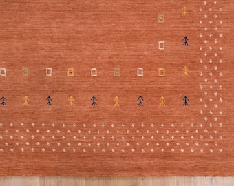 May include: A close-up of a rust-colored rug with a geometric pattern in shades of white, yellow, green, and blue. The pattern includes small squares, arrows, and dots.