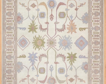 May include: A cream-colored rug with a floral pattern in shades of pink, blue, green, and yellow. The rug has a border with a geometric pattern in brown and beige.
