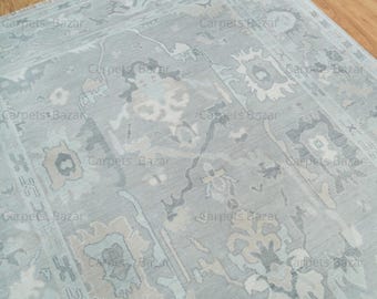 May include: A light blue rug with a traditional Persian design. The rug has a subtle pattern of flowers and leaves in shades of beige and gray.