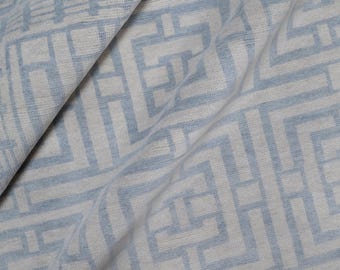 May include: Close-up of a light blue and white fabric with a geometric pattern. The fabric is draped, showing folds and texture. The design features a repeating maze-like pattern in light blue.