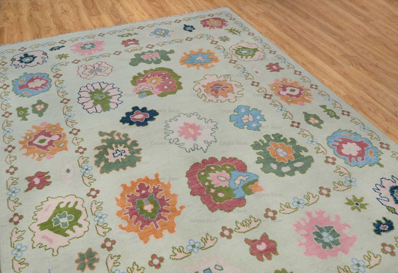 May include: A light green rug with a floral pattern. The rug features a variety of colors, including pink, blue, orange, and green. The flowers are arranged in a symmetrical pattern.