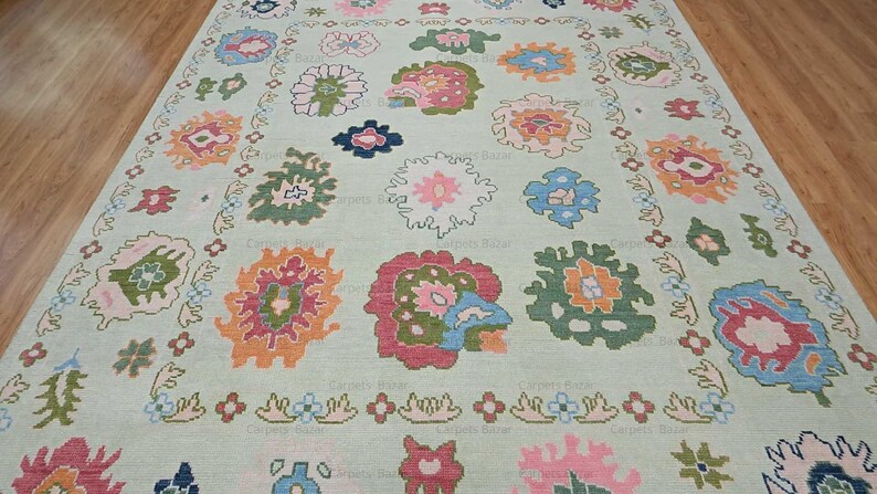 May include: A light green rug with a floral pattern. The rug features a variety of colors, including pink, blue, green, and orange. The flowers are arranged in a symmetrical pattern.