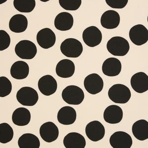 Könnte beinhalten: Ein Textilmuster mit einem sich wiederholenden Design aus unregelmäßigen, handgezeichneten schwarzen kreisförmigen Formen, die auf einem einfarbigen cremeweißen Hintergrund verteilt sind. Die schwarzen Punkte variieren in Größe und Form.